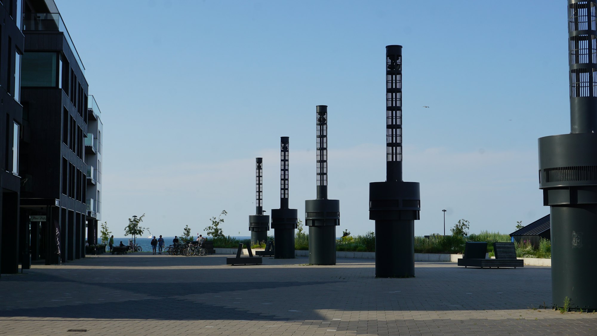 Open seaside public square in Tallinn with tall dark sculptures under a clear sky