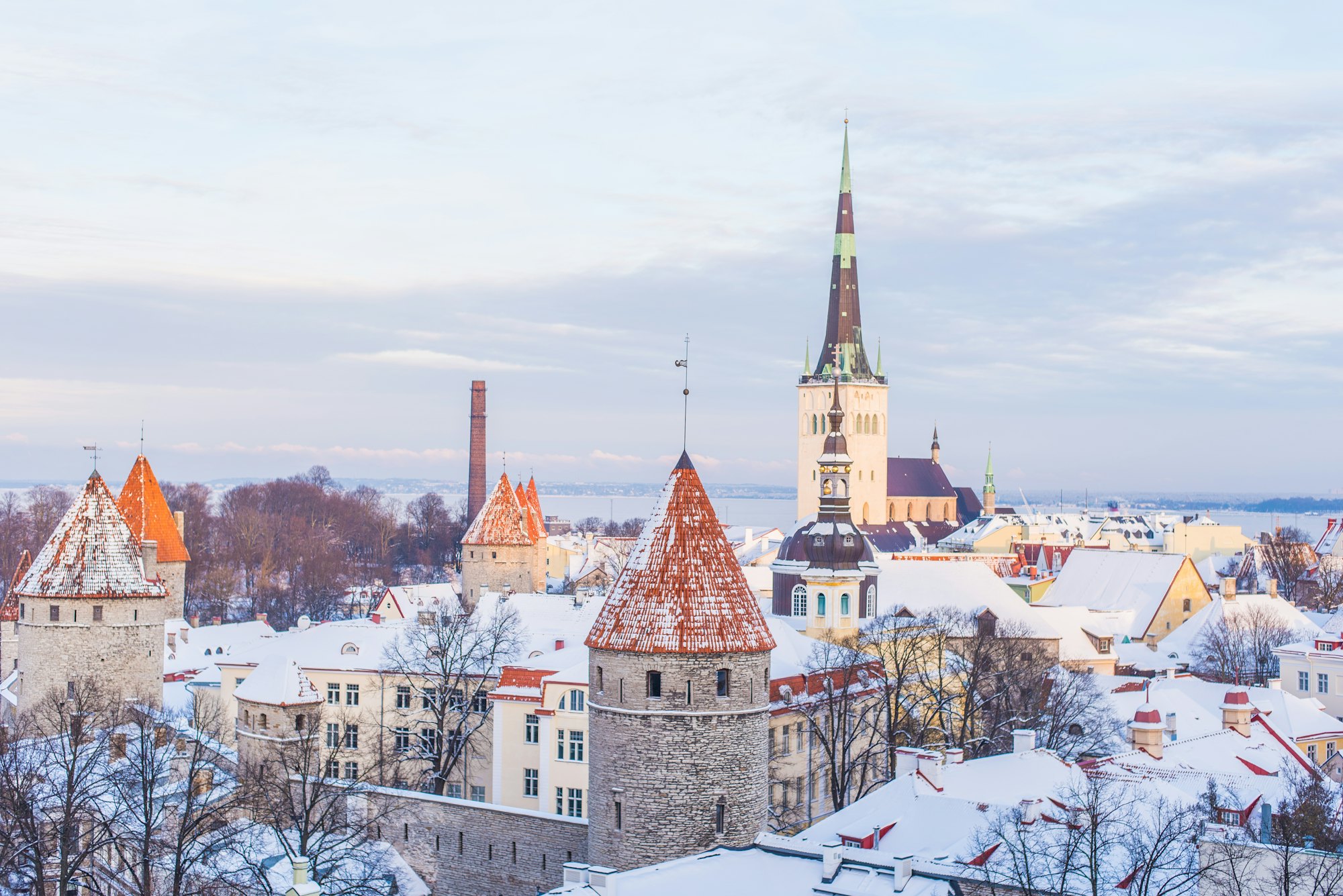 Snow-covered rooftops and towers of Tallinn Old Town with St Olaf's spire in soft winter light