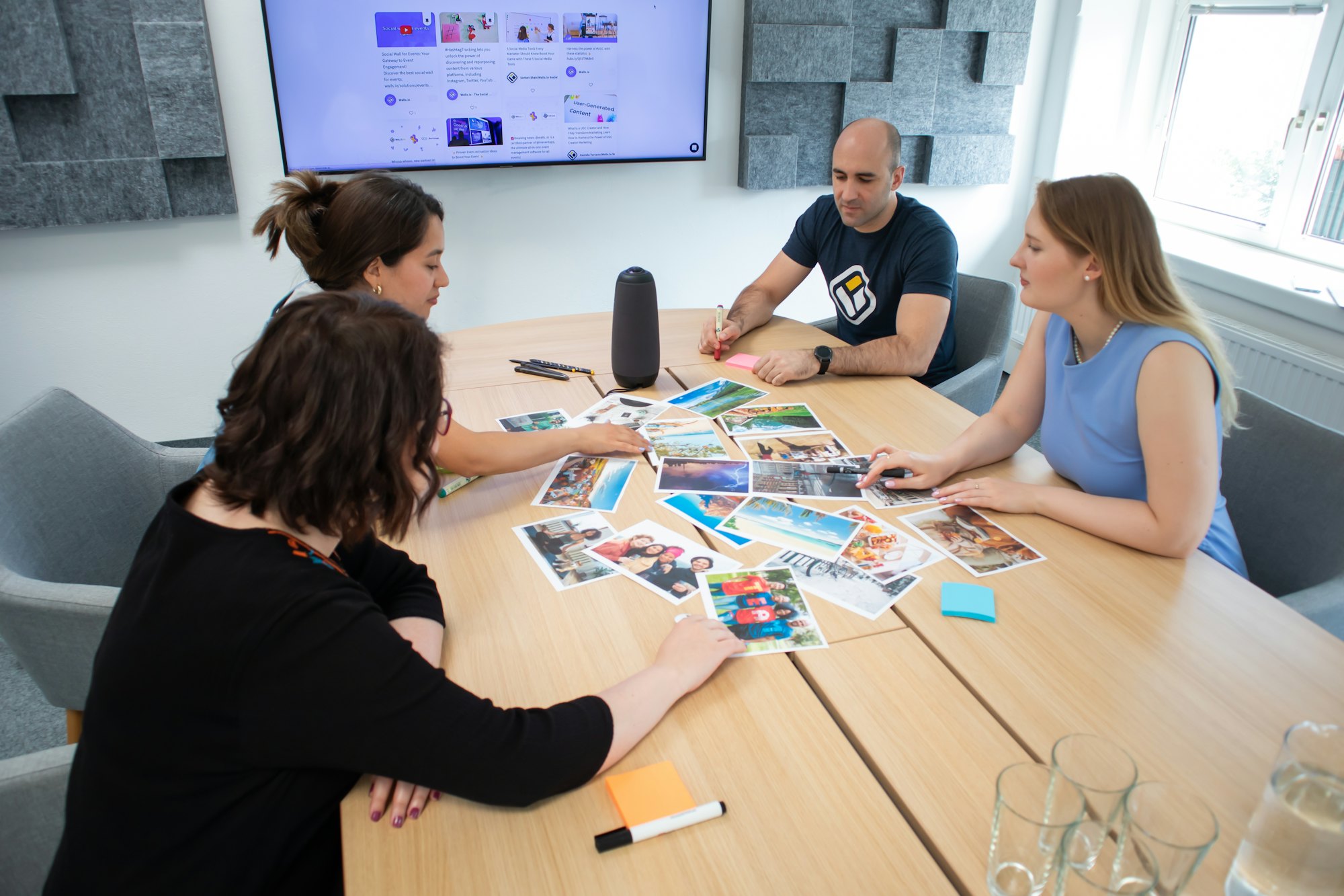 Four colleagues around a wooden table sorting printed cards in a bright meeting room